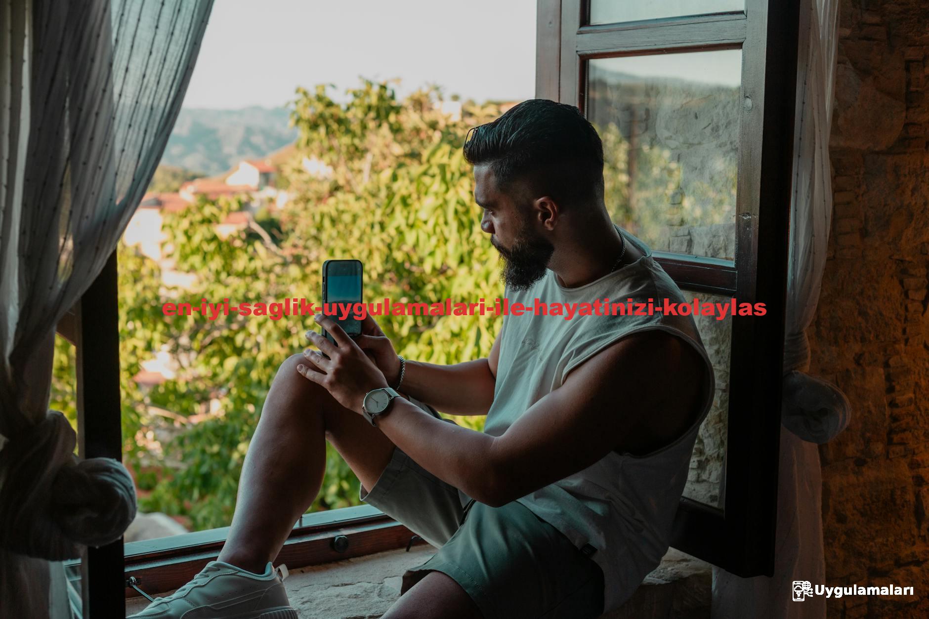 Man sitting on windowsill using phone, enjoying a scenic view. Perfect for lifestyle or travel themes.