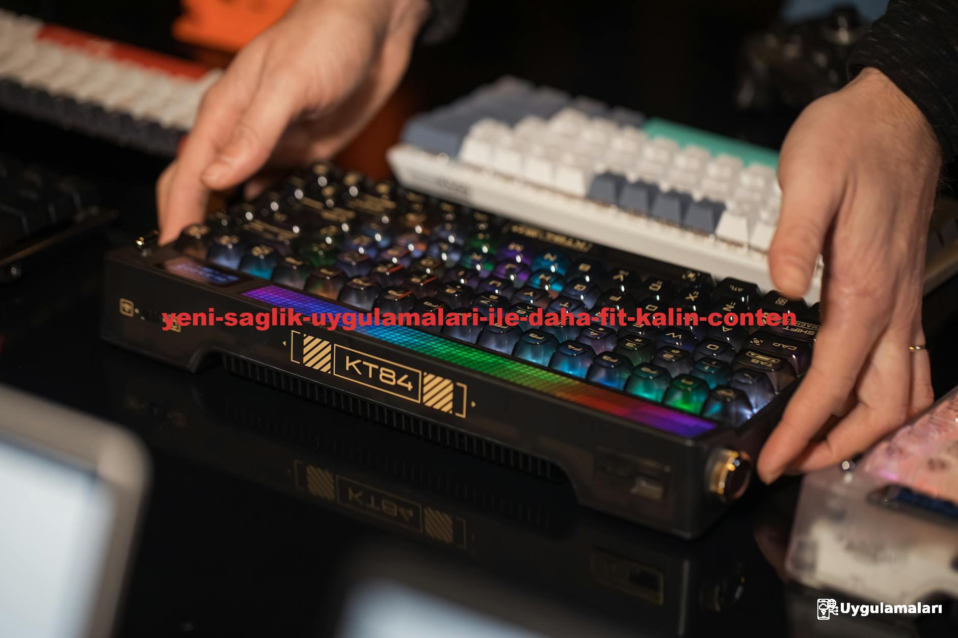 Hands adjusting an RGB mechanical keyboard among other keyboards on a desk.