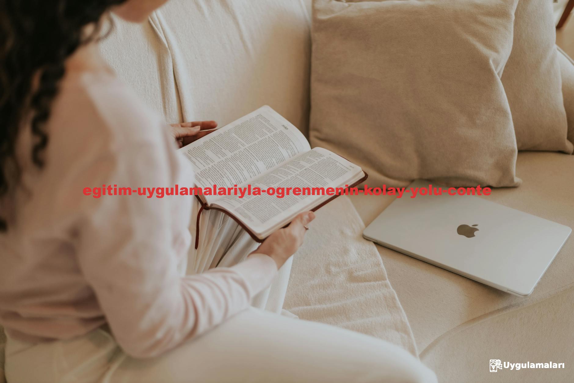 Woman reading a book on a cozy sofa with a laptop nearby. Ideal for lifestyle and relaxation themes.