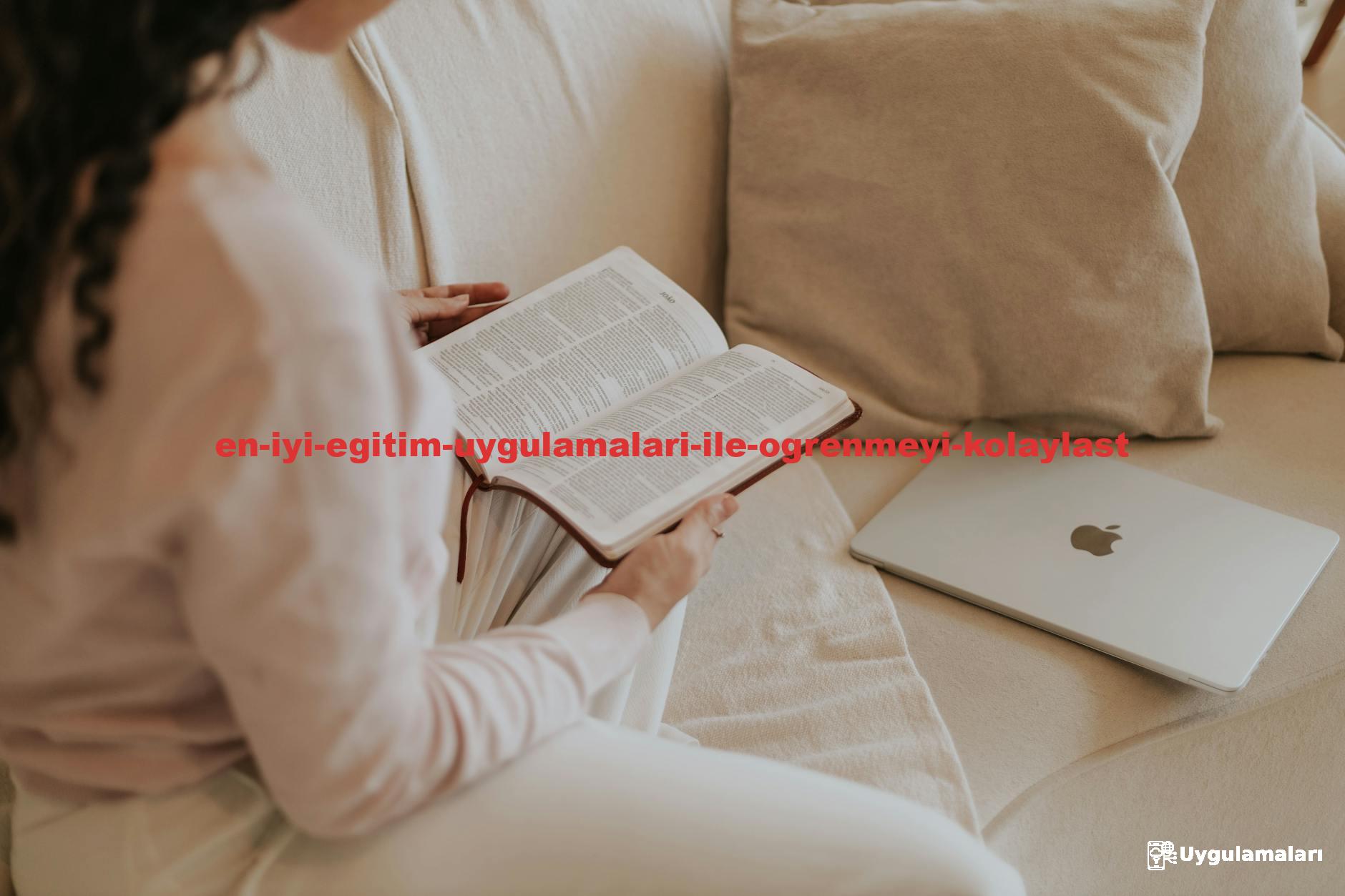 Woman reading a book on a cozy sofa with a laptop nearby. Ideal for lifestyle and relaxation themes.