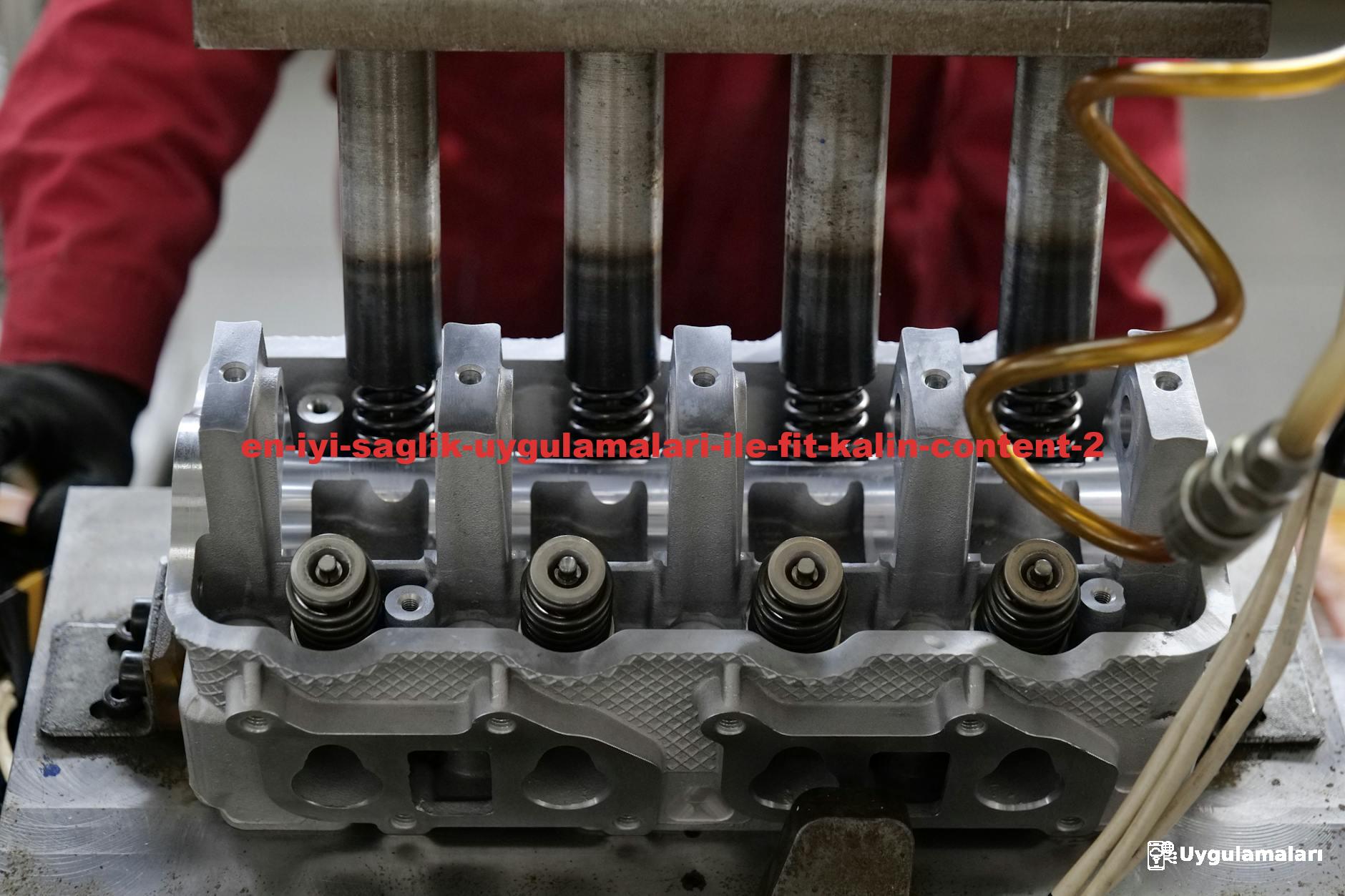 Detailed view of a metallic engine cylinder head with springs and pistons, assembled in an industrial workshop.