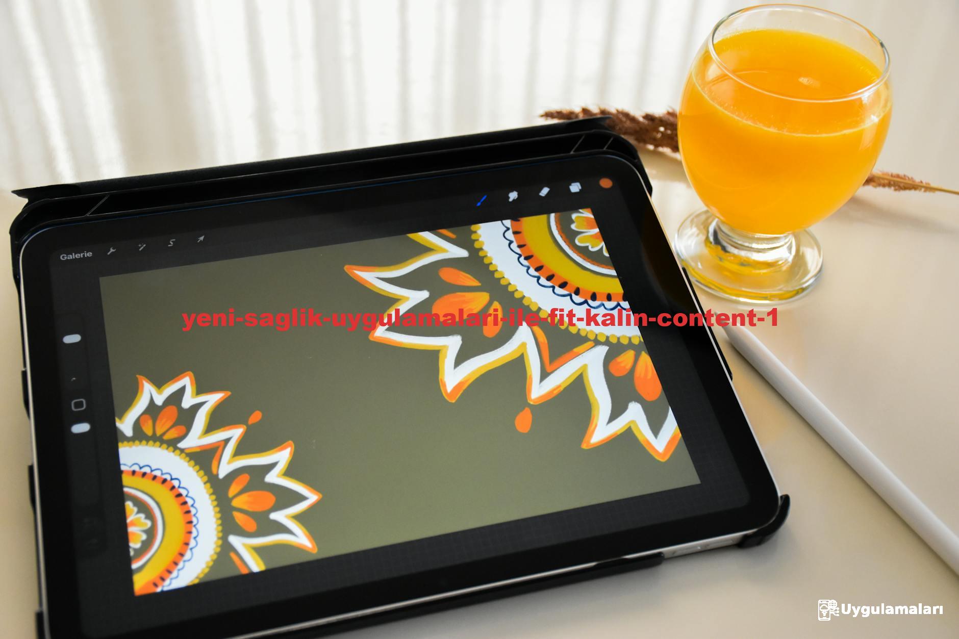 A tablet displaying mandala artwork beside a glass of orange juice on a table.