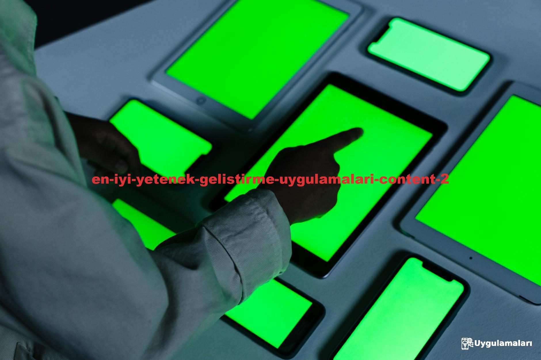 Person interacting with multiple green-screen electronic devices indoors.