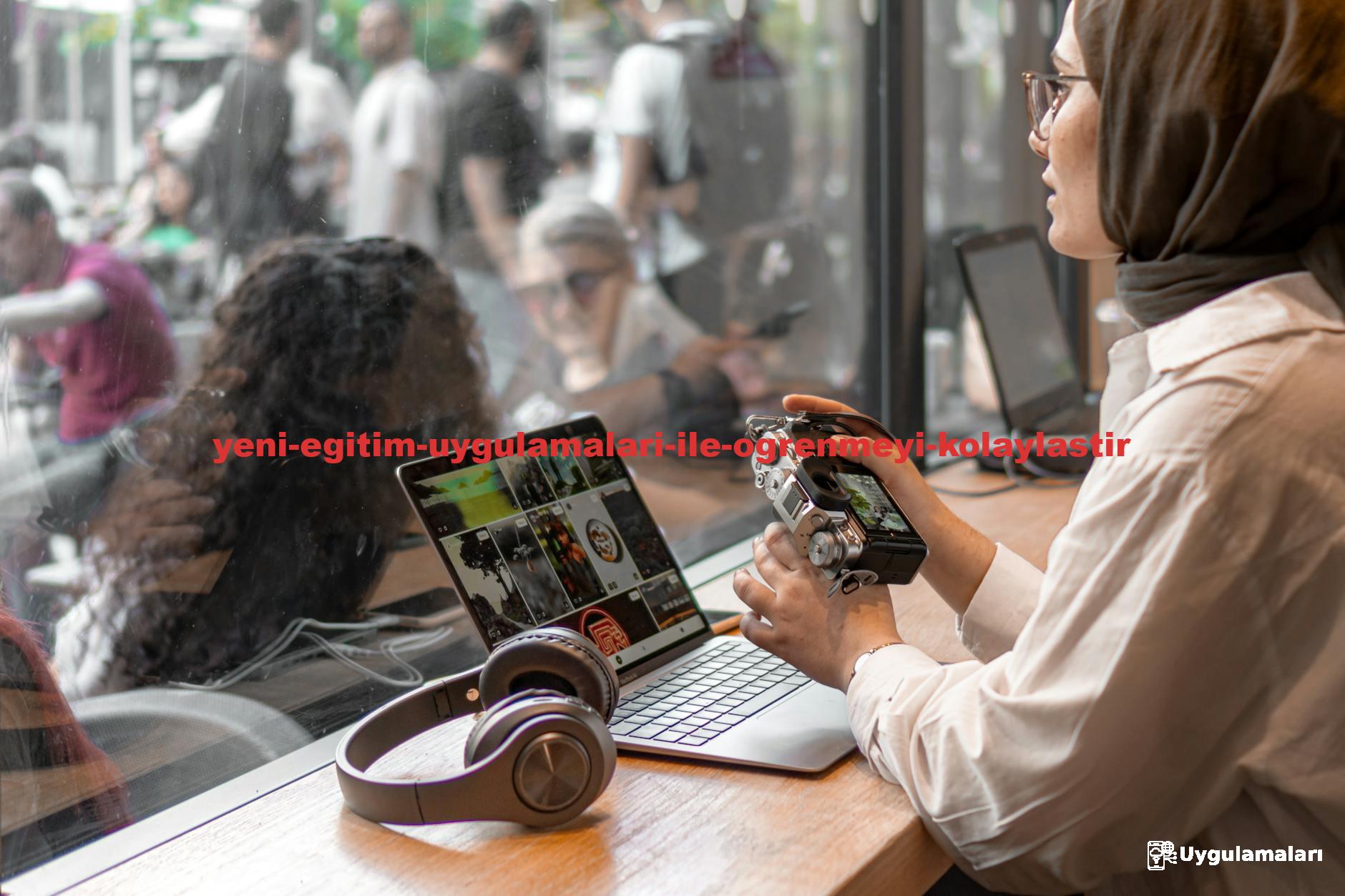 A woman in a hijab using a laptop and camera in a cafe setting, illustrating remote work.