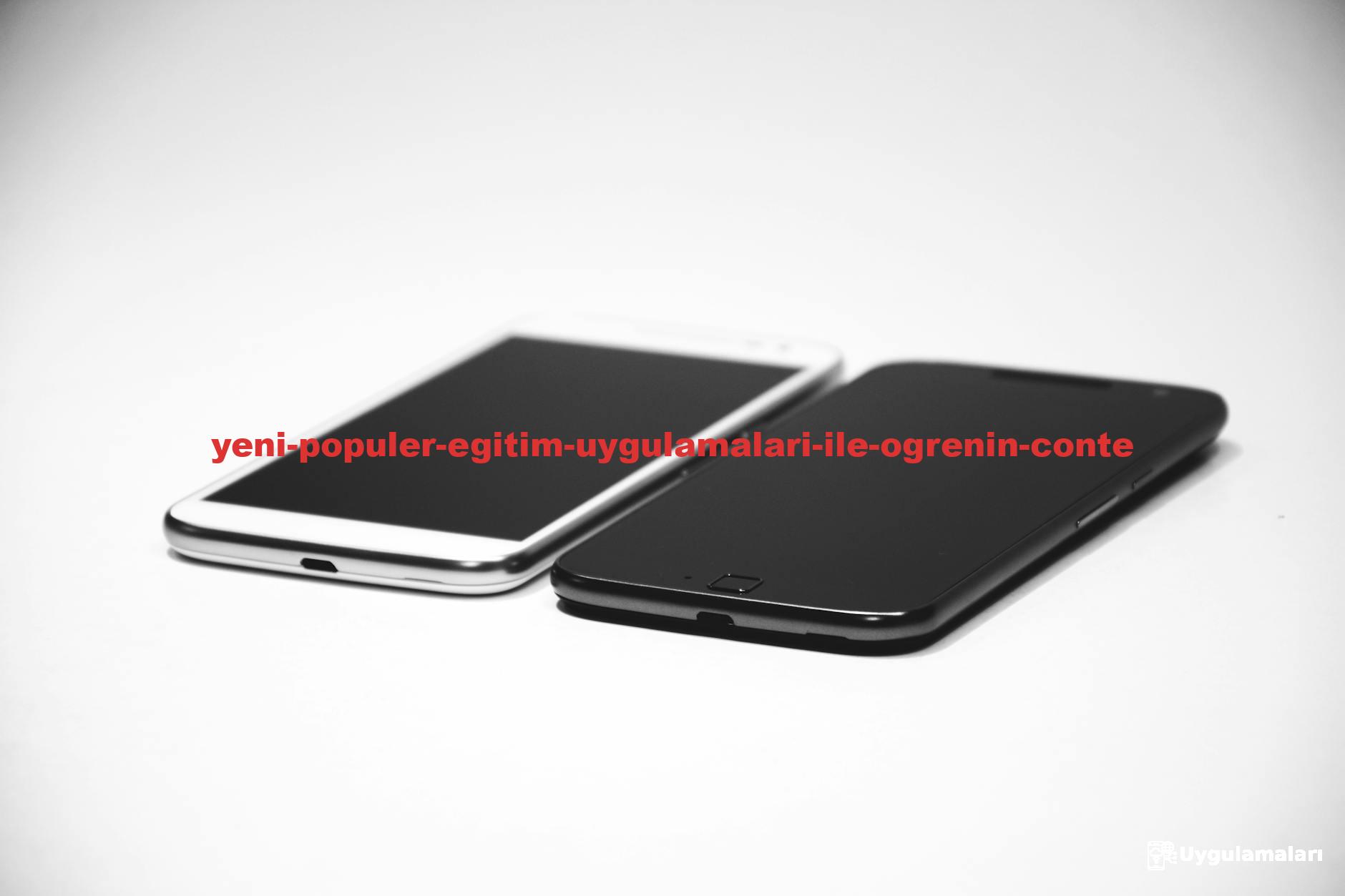 Two smartphones, one black and one white, placed on a white surface, showcasing modern design.